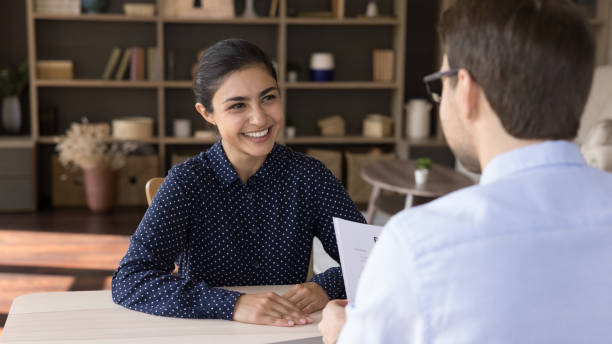 Happy female job seeker holding interview with male leader, making good first impression at meeting, discussing working offer in modern office, employment concept.